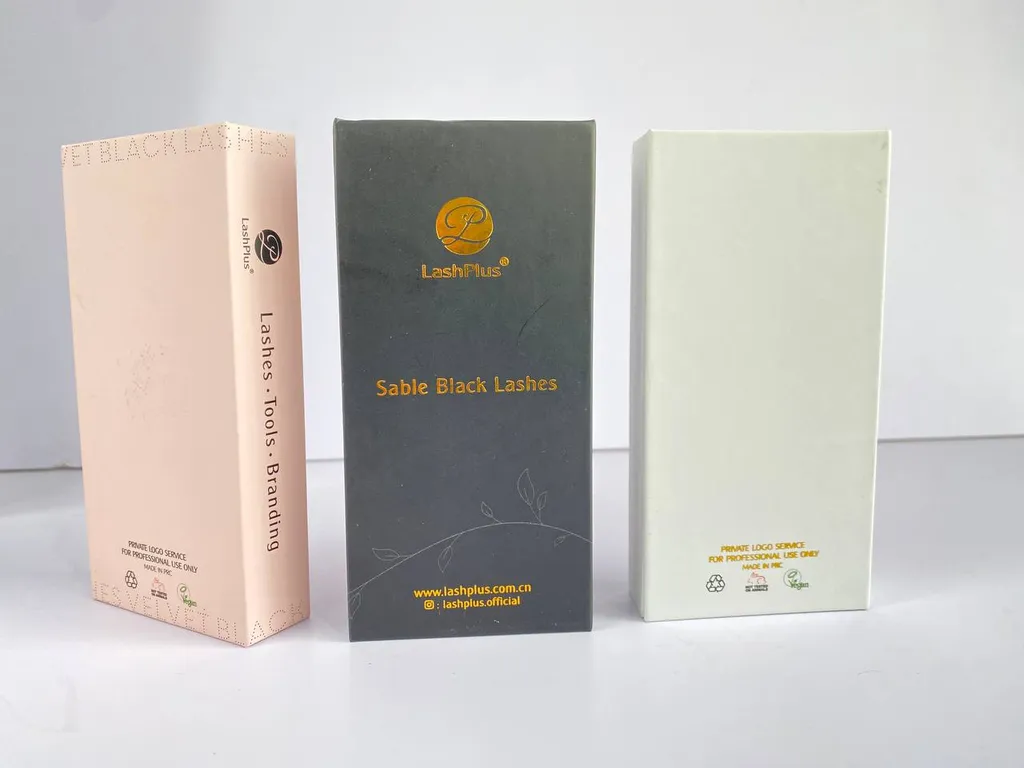 Three custom lash boxes side by side — matte pink, foil-logo black rigid, and cream — from our own lash line